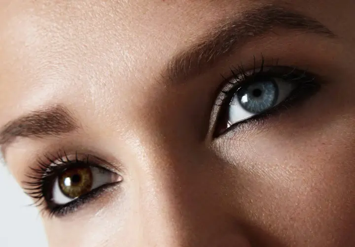 Oczy z heterochromią centralną: jedno błękitne, drugie brązowe. Rzęsy podkreślone tuszem.