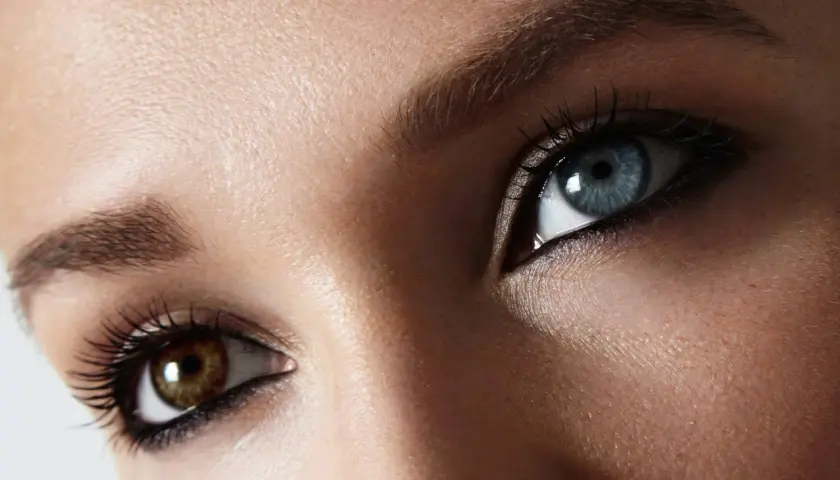 Oczy z heterochromią centralną: jedno błękitne, drugie brązowe. Rzęsy podkreślone tuszem.